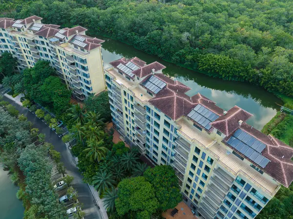 Huzurlu bir göle bakan, yemyeşil bir ormanın içine yerleştirilmiş modern tatil köyü apartmanları. Hainan ili, Çin. 