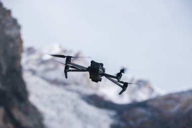 close-up of a drone in mid-air, flying against a background of snowy mountains
