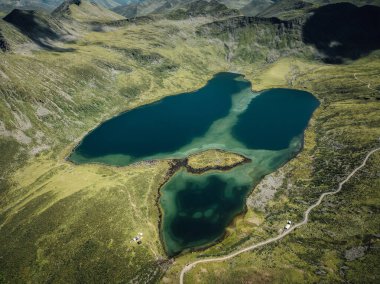 Aerial view of vibrant blue lake nestled in a rugged, grassy landscape.