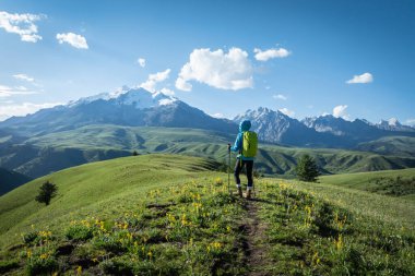 Sırt çantalı bir kadın dağlarda yürüyüş yapıyor.