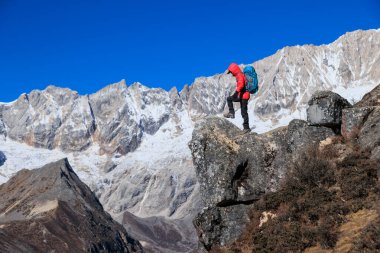 Başarılı kadın yürüyüşçü yüksek rakımlı dağın tepesine tırmanıyor.