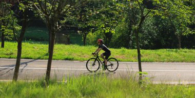 Mavi formalı bir kadın bisikletçi dağlardaki bir ormanın içinden bisikletini sürüyor. 