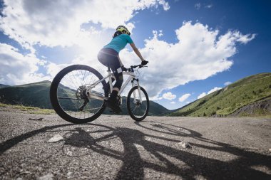 Dağlarda bisiklet süren bir kadın Uçsuz bucaksız gökyüzünün altında 
