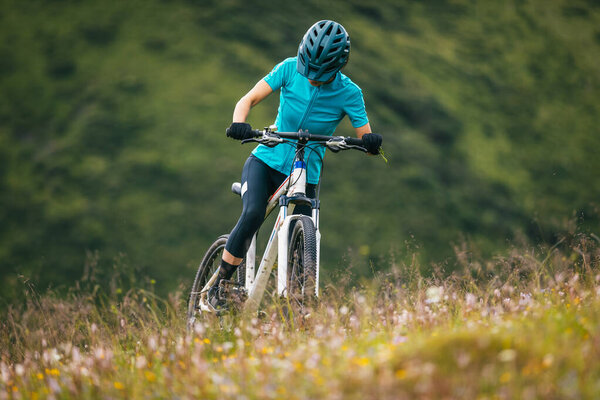 female cyclist rides her bike in mountains fields 