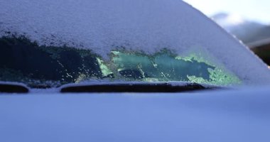 Bir arabanın ön camına yakın çekim soğuk havada kısmen taze kar ve buzdan temizlendi.