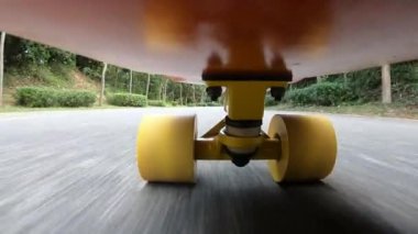 Asfalt üzerinde sarı tekerlekleri olan hareket eden bir kaykayın aşırı yakın çekim, alçak açılı görüntüsü.