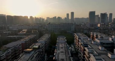 Yoğun bir şehir silueti ve merkez yol üzerinde puslu, sıcak gün batımı ya da gün doğumu manzarası. Çin