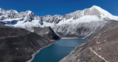 Karlı dağlarla çevrili bir vadide mavi bir göl 