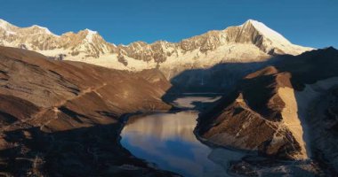 Gün doğumunda karlı dağlarla çevrili bir vadide güzel bir göl..