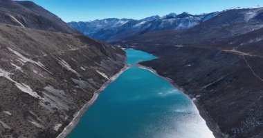 Karlı dağlarla çevrili bir vadide mavi bir göl 