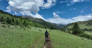 Dağ bisikletçisi çimenli bir patikadan iniyor..