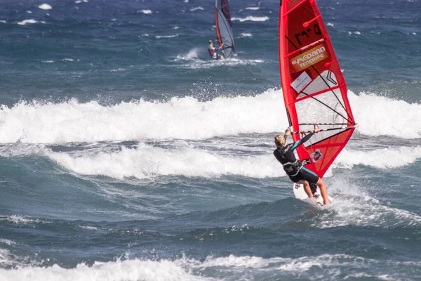 Tenerife-İspanya-Temmuz 2013: Kırmızı yelkenli rüzgar sörfü tahtasıyla okyanusta dalgıç kıyafetli genç bir adam. Tenerife, Kanarya Adaları, İspanya