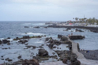 Martianez Gölü manzarası. Uçurumun taşları. Dalgalar uçurumun volkanik kayalarına çarpıyor. Dalgalı okyanus. Siyah kayalar. Puerto de la Cruz, Tenerife, Kanarya Adaları, İspanya.