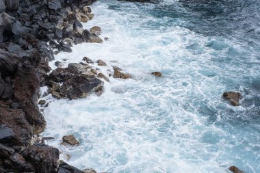 Uçurumun taşları. Dalgalar uçurumun volkanik kayalarına çarpıyor. Dalgalı okyanus. Siyah kayalar. Puerto de la Cruz, Tenerife, Kanarya Adaları, İspanya.