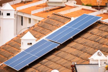 Tek aile evlerinin çatısında bir grup güneş paneli. Güneş panelleri. Temiz enerji. Ekoloji. Kırmızı kiremitler. Tenerife, Kanarya Adaları, İspanya