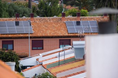 Kırmızı tuğlaları ve kırmızı fayansları olan tek bir aile evinin çatısındaki güneş panelleri. Tenerife, Kanarya Adaları, İspanya