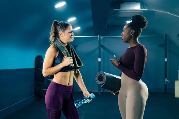 Two fit women in sportswear talking in the gym after workout.