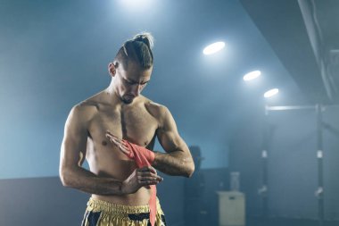 Muay Thai boxer preparing bandages for training.