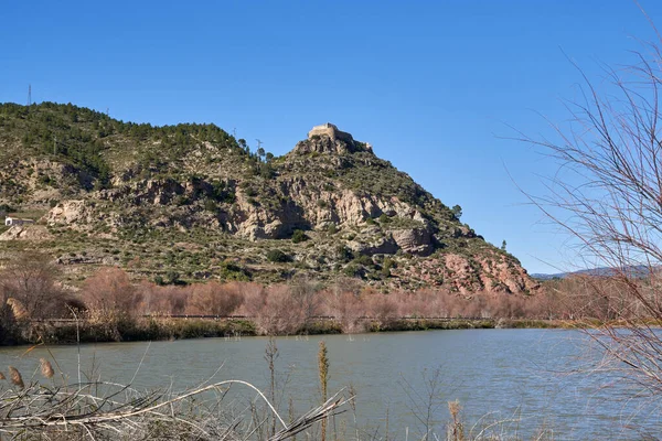 Beautiful view of a mountain landscape with the Castillo de Domeo on the top of the mountain and the Turia river in the foreground, in Valencia, Spain