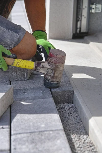 Paver with rubber mallet and paving stones on construction site - construction industry