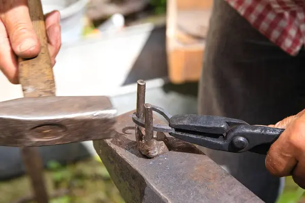 铁匠一边工作一边用铁锤和钳子打铁锤 — 图库照片