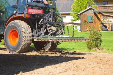 Tine harrow 'lu küçük traktör toprakta çalışıyor.