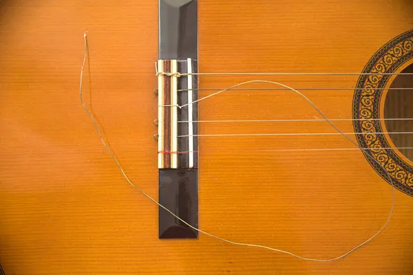 broken string of classical musical instrument guitar - closeup