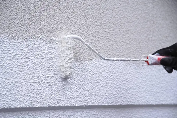 Painter painting wall with paint and paint roller - skilled trade