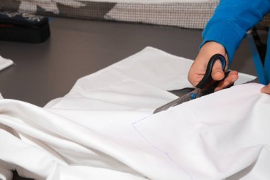 Atölyede tekstil üzerine çalışan bir terzi. Yakın plan el işi.