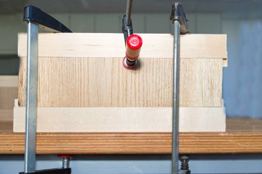 Bir marangoz atölyesinde vida kıskaçları dil ve oyuk ile ahşap parçaları birbirine bastırır