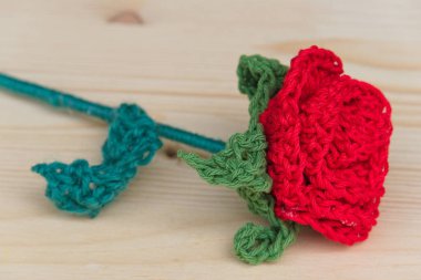 Üç boyutlu tığ işi, ahşap bir tabakta kırmızı gül.