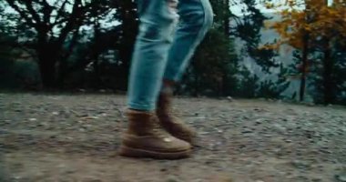 Gezgin botları, sonbahar tatilinde bulutlu ve yağmurlu bir günde çakıllı dağ yolunda yürür. Çaktırmadan el kamerasıyla çekilen kadın ayağı maceraya çıktı.. 