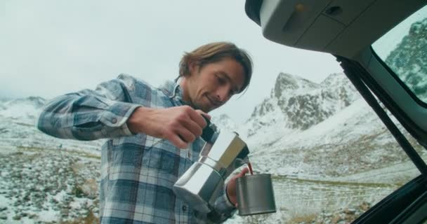 美しい山の風景で冬の休暇にカップにモカ鍋からコーヒーを注ぐキャンプロードトリップの男性 冬の週末旅行の男性旅行者 — ストック動画