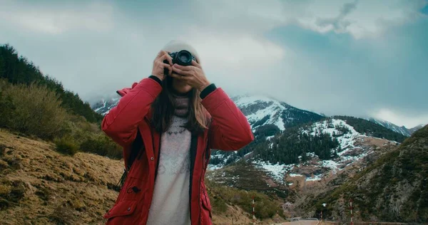 Kırmızı ceketli gezgin kadın klasik kamerada fotoğraf çekiyor. Seyahat fotoğrafçısı kış tatilinde içerik yaratıyor. 