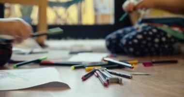 Çocukların odaksız yakın plan fotoğrafları oturma odasında yere oturup renkli kalemle çiziyorlar. Erkek ve kız kardeş evin içinde. 