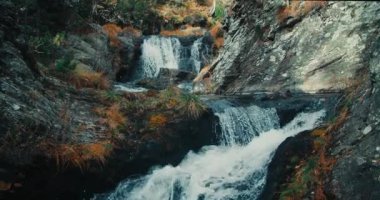 Güzel dağ nehri şelalesinin yavaş çekim rahatlama görüntüsü. Dere çağlayanlarındaki kayalıklarda akan ve su sıçrayan 