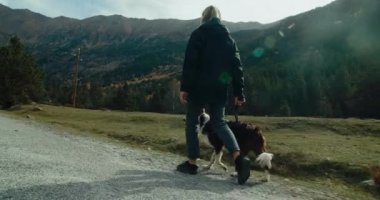 Sınırda gezintiye çıkmış bir kadın tasmalı bir çoban köpeğiyle. Gezgin kadın dağ yolculuğunda evcil hayvanla yolda yürüyor.. 