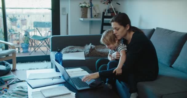 娘が気を散らしながら家で働くフリーランスのビジネスウーマン リビングルームでラップトップコンピュータを使用している女性 — ストック動画