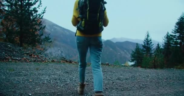 低キーは 若い大人の女性が雨の日に休暇旅行で山の端に歩くショット バックパッカーの観光客は山道での旅行を楽しむ — ストック動画