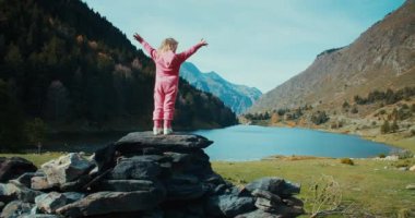 Tatil gezisindeki küçük kız ellerini kaldırarak kaya üzerinde duruyor. Çocukluk ve seyahat özgürlüğü kavramı silahlansın. 