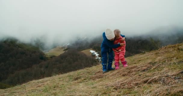 Zwei Kinder Stehen Bei Bewölktem Himmel Auf Dem Berg Und — Stockvideo