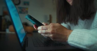 Evde dizüstü bilgisayar ve cep telefonu kullanan serbest çalışan kadınlar. İş kadını gece ev ofisinde akıllı telefon işi yapıyor.