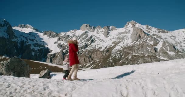 子供を持つ女性は冬の休暇旅行で雪の上を歩く 家族は山の旅で休暇を楽しむ — ストック動画