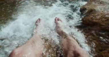 Yaz tatilinde Dağ nehri şelalesinde ayaklar. Su sıçramalarında gevşeme 