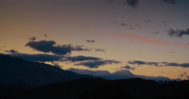 Clouds on orange sky moving on timelapse cloudscape shot at mountain landscape