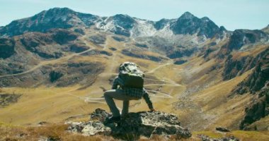 Serbest çalışan bir adam sırt çantasıyla dağ yolundaydı kaya üzerinde oturur ve destansı dağ manzarasında dizüstü bilgisayar kullanırdı.