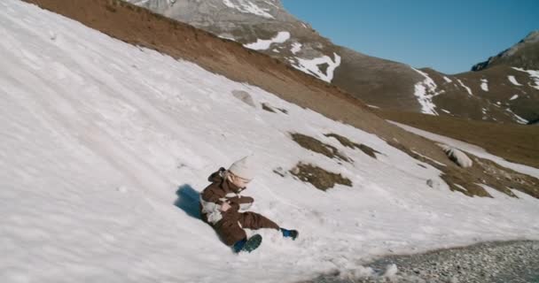 山の旅アドベンチャースライディング雪の丘で陽気な少年をスローモーションショット — ストック動画
