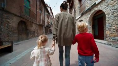 Çocuklar, annelerini el ele tutuşarak gezmeye çıkarlar. Tatildeki aile turizmi 