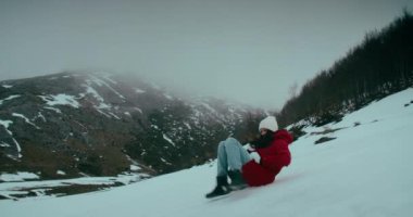 Kış tatili gezisinde olan genç bir kadın dağ kayağında eğleniyor. Neşeli kadın karda babasının üzerinde kayıyor.. 