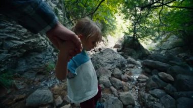 Küçük bir kızın dağ yolunda yürümesine yardım eden bir adamın pov çekimi. Yolculukta babalara yardım etmek. Birinci şahıs bakış açısı. 